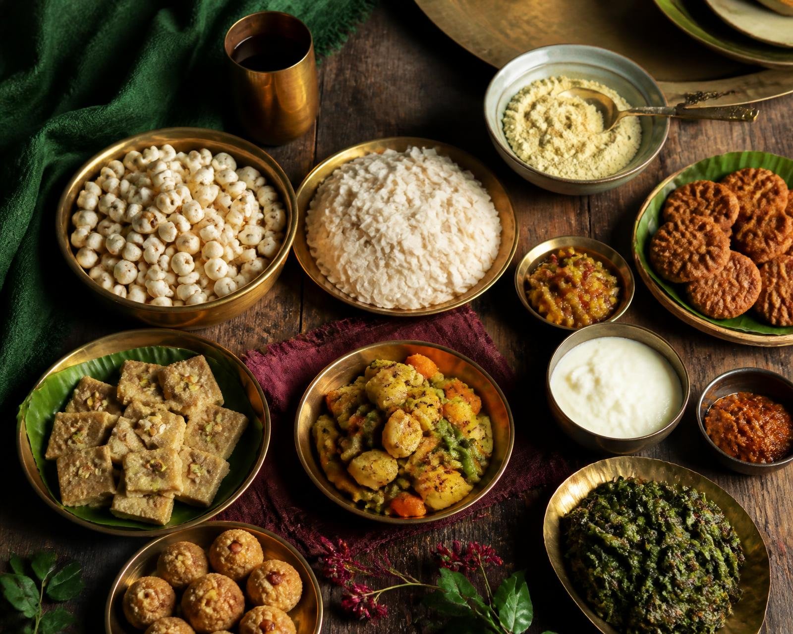 A table of foods associated with Mithila including makhana, chura, sattu, dahi, thekua, saag, pickles, vegetables and sweets